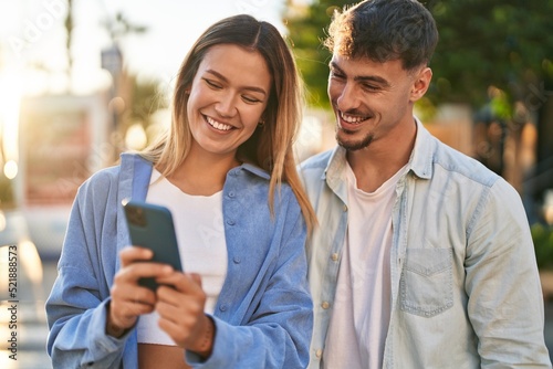 Young man and woman couple smiling confident using smartphone at street © Krakenimages.com