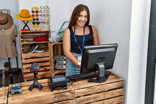 Young hispanic woman smiling confident working at clothing store