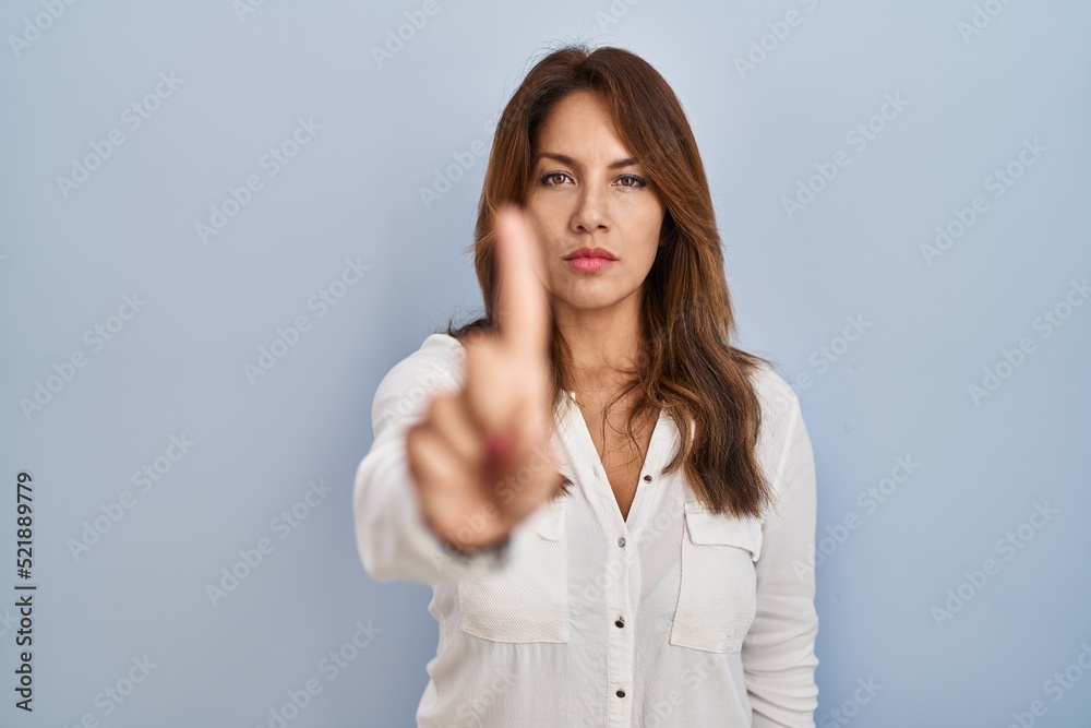 Hispanic woman standing over isolated background pointing with finger up and angry expression, showing no gesture Hispanic woman standing over isolated background pointing with finger up and angry expression, showing no gesture