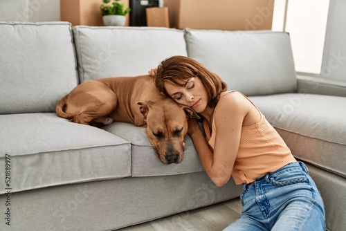 Young caucasian woman sleeping sitting on floor with dog at home