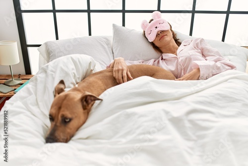 Young caucasian woman sleeping lying on bed with dog at bedroom