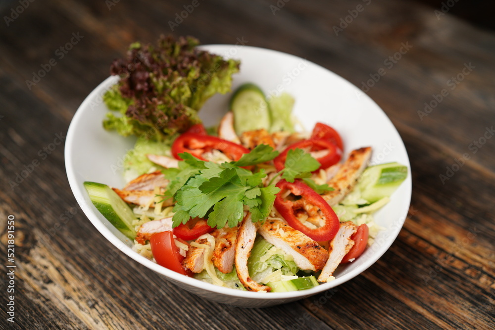 Salad with fried chicken. Salad made with fried chicken, tomatoes, cucumber, green pepper, and grated cheese in a white bowl. Delicious health food. Salad with fried chicken. Salad made with fried chicken, tomatoes, cucumber, green pepper, and grated cheese in a white bowl. Delicious health food.