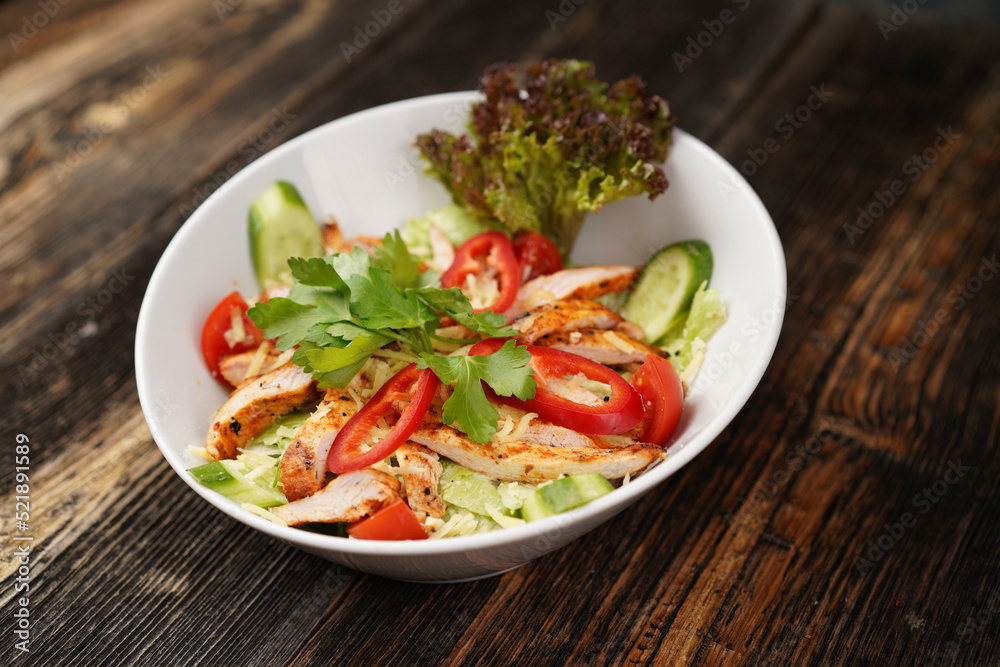 Salad with fried chicken. Salad made with fried chicken, tomatoes, cucumber, green pepper, and grated cheese in a white bowl. Delicious health food. Salad with fried chicken. Salad made with fried chicken, tomatoes, cucumber, green pepper, and grated cheese in a white bowl. Delicious health food.