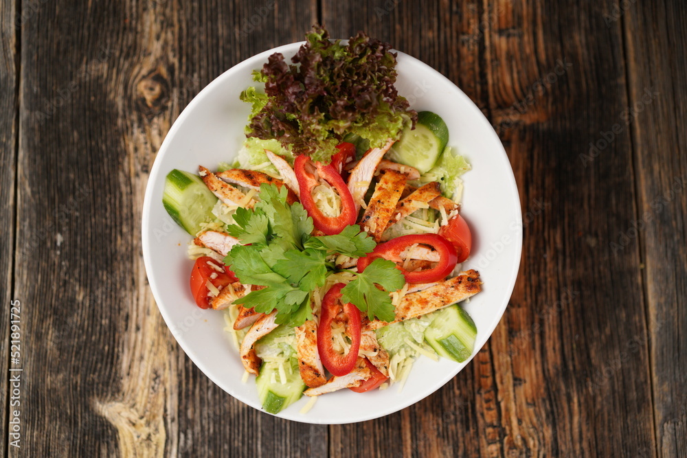 Salad with fried chicken. Salad made with fried chicken, tomatoes, cucumber, green pepper, and grated cheese in a white bowl. Delicious health food. Salad with fried chicken. Salad made with fried chicken, tomatoes, cucumber, green pepper, and grated cheese in a white bowl. Delicious health food.