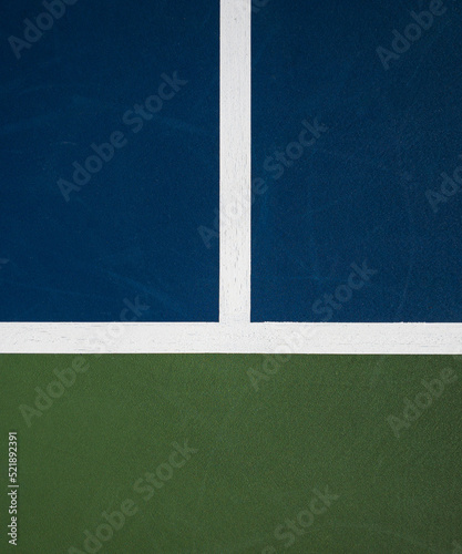 Tennis hard court colored green and blue with white baseline and doubles line
