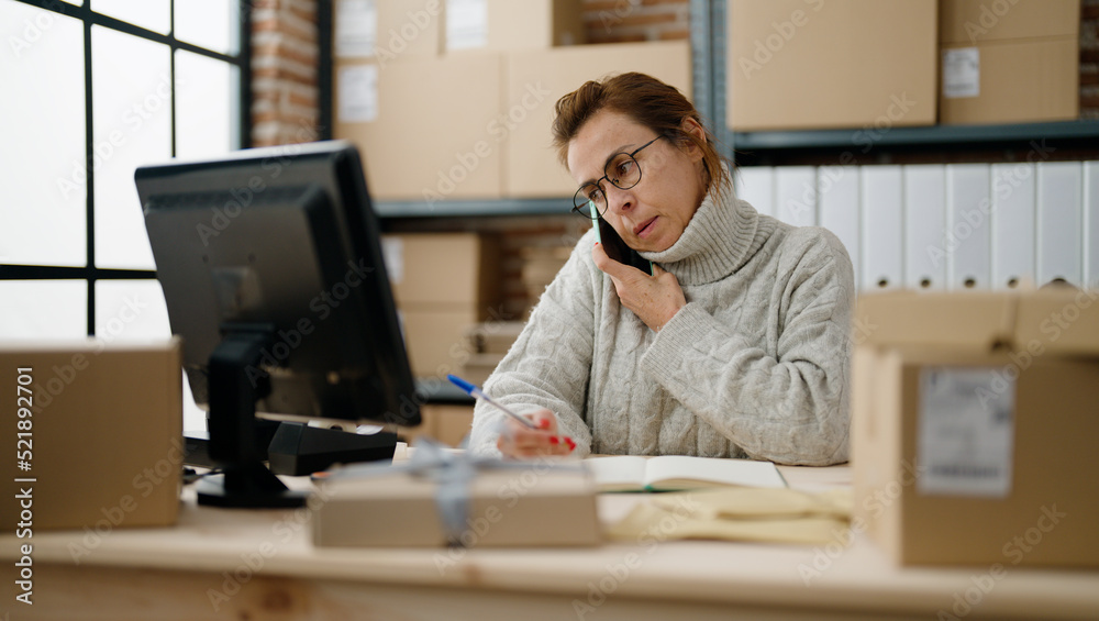 Middle age hispanic woman ecommerce business worker talking on the smartphone at storehouse office Middle age hispanic woman ecommerce business worker talking on the smartphone at storehouse office