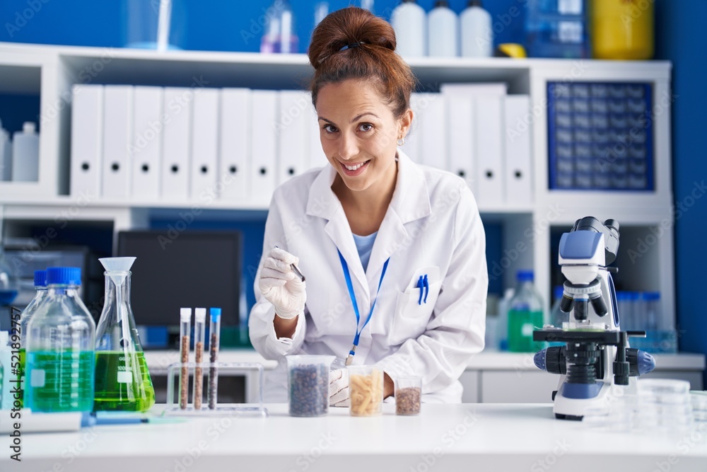 Young woman scientist holding tweezer standing at laboratory