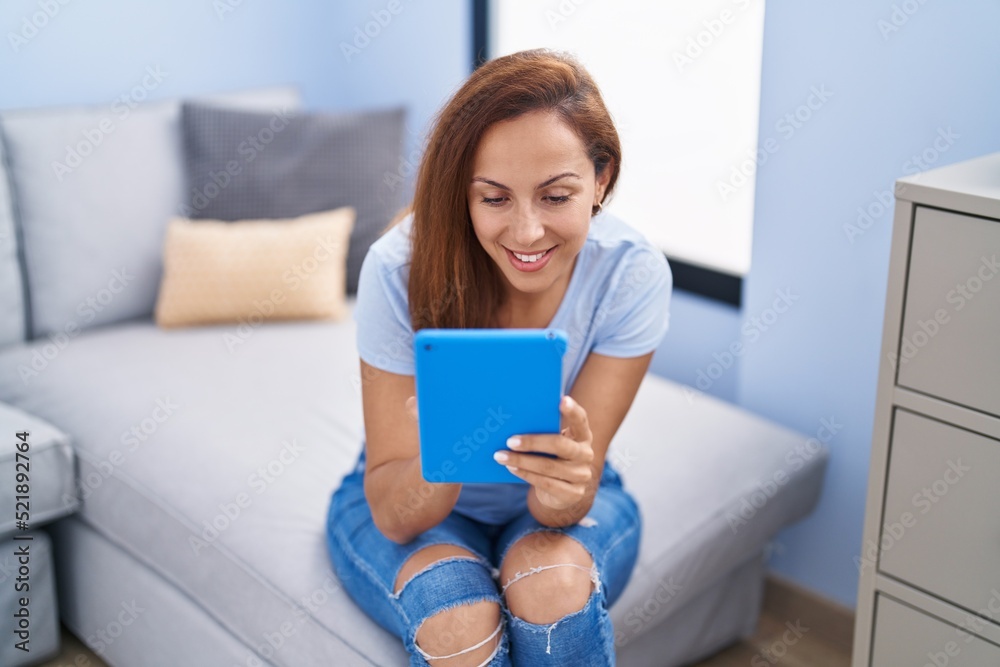 Young woman using touchpad sitting on sofa at home Young woman using touchpad sitting on sofa at home