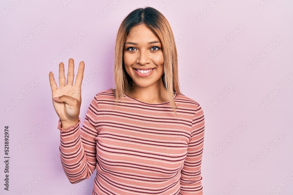 Beautiful hispanic woman wearing casual striped sweater showing and pointing up with fingers number four while smiling confident and happy. Beautiful hispanic woman wearing casual striped sweater showing and pointing up with fingers number four while smiling confident and happy.