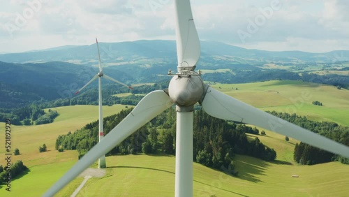 Zoom out of camera from a propeller of the windmill in the field with mountains on the background. photo