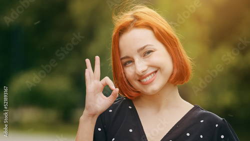 Fotografie Female outdoors portrait happy caucasian woman model feminine lady shows okay ha