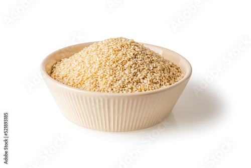 White sesame seeds in a beige bowl isolated on a white background. Heap of organic til grains on a plate cutout. Sesamum indicum crop for boosting immunity diet and calcium source. © Maryia