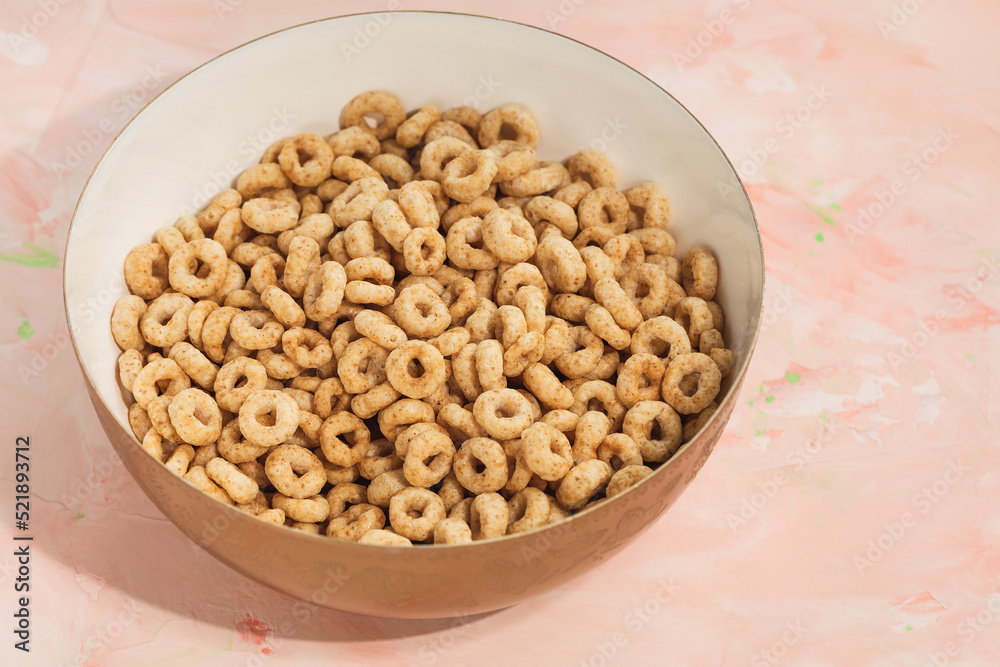 Delicious honey cheerios cereal in a bowl on pink background. Close-up, flat lay, copy space. Breakfast concept