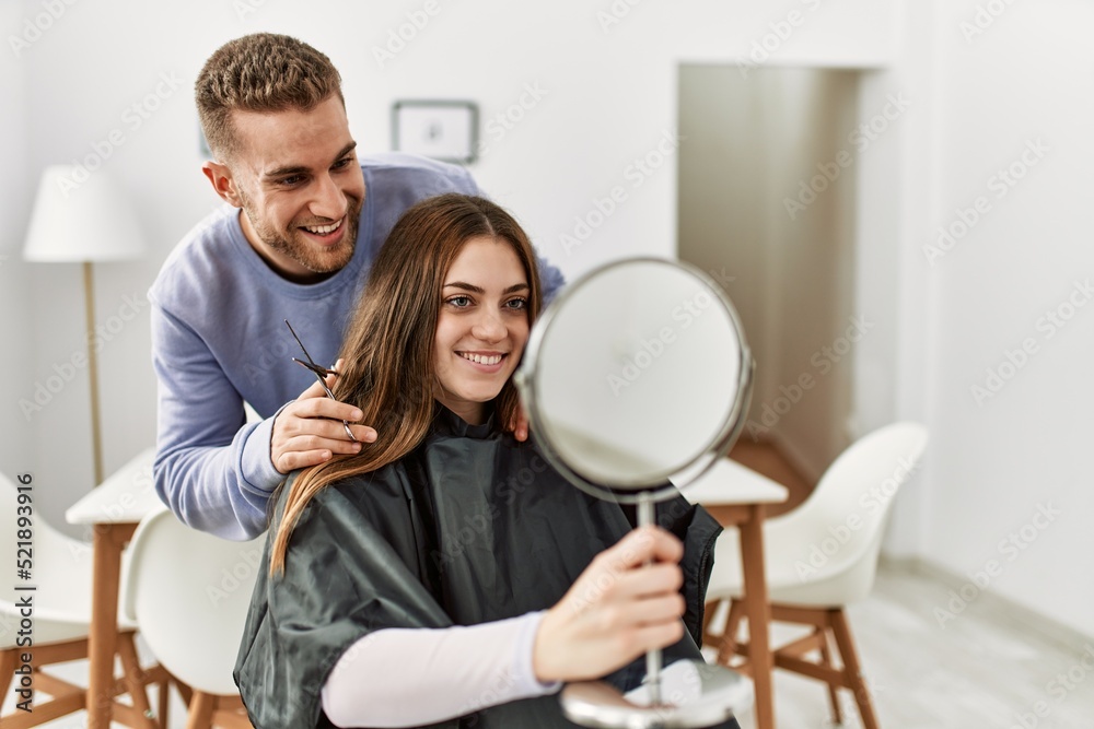Young man cutting hair his girlfriend at home.