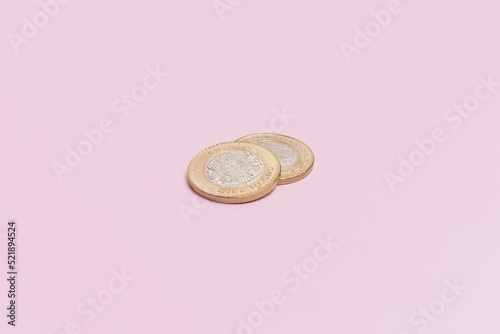 Dos monedas de 10 pesos mexicanos sobre fondo rosa.