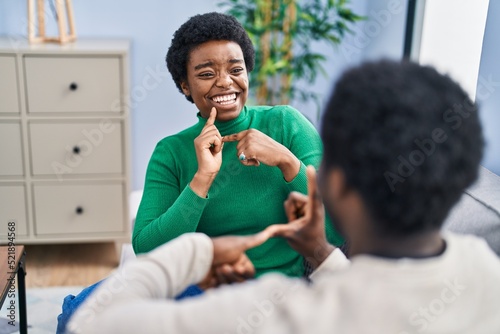 African american man and woman couple speaking with deaf language at home