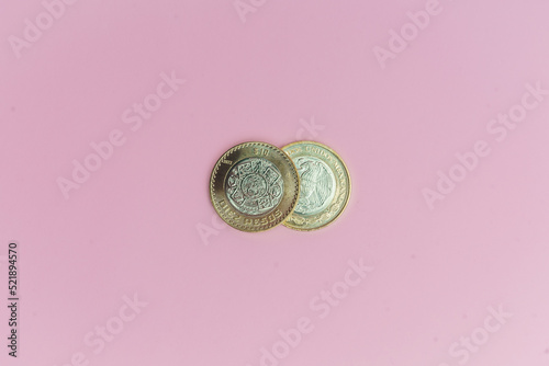 Dos monedas de 10 pesos mexicanos sobre fondo rosa.