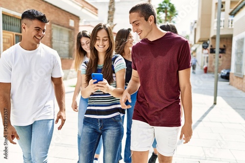 Group of young friends smiling happy using smartphone walking at the city.