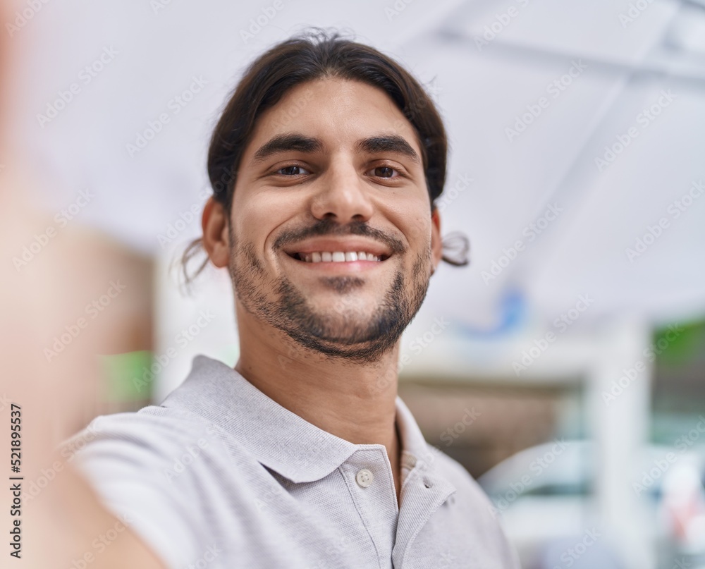 Young hispanic man smiling confident making selfie by the camera at street