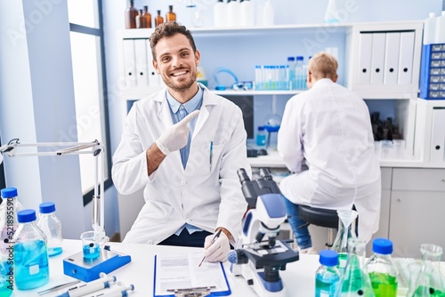Hispanic man and woman working at scientist laboratory smiling happy pointing with hand and finger
