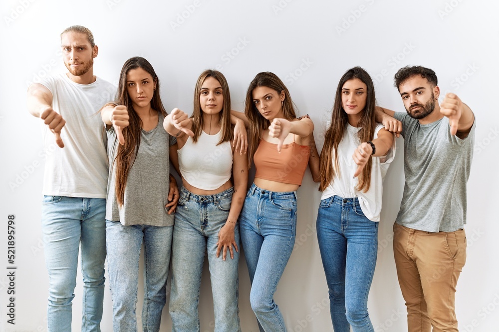 Group of young friends standing together over isolated background looking unhappy and angry showing rejection and negative with thumbs down gesture. bad expression. Group of young friends standing together over isolated background looking unhappy and angry showing rejection and negative with thumbs down gesture. bad expression.