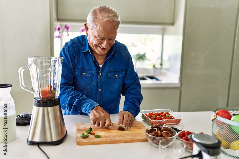 Senior man smiling confident cutting datil at kitchen Senior man smiling confident cutting datil at kitchen