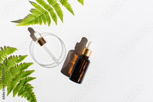 Petri dishes, cosmetic glass bottles on white background.Natural medicine, cosmetic research, bioscience, organic skin care products. Top view, flat lay, copy space. Scientific laboratory glassware.