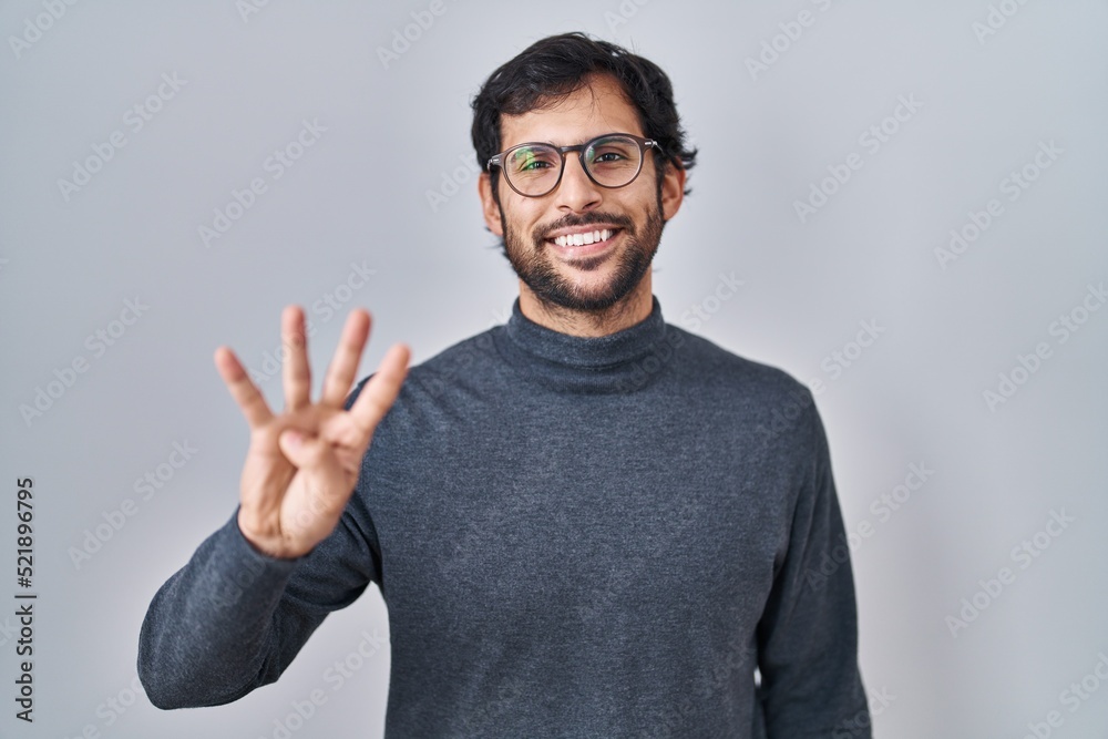 Handsome latin man standing over isolated background showing and pointing up with fingers number four while smiling confident and happy. Handsome latin man standing over isolated background showing and pointing up with fingers number four while smiling confident and happy.