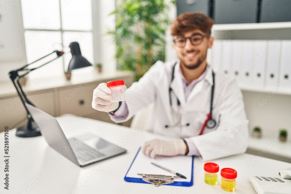 Young arab man wearing doctor uniform holding test tube at clinic Young arab man wearing doctor uniform holding test tube at clinic
