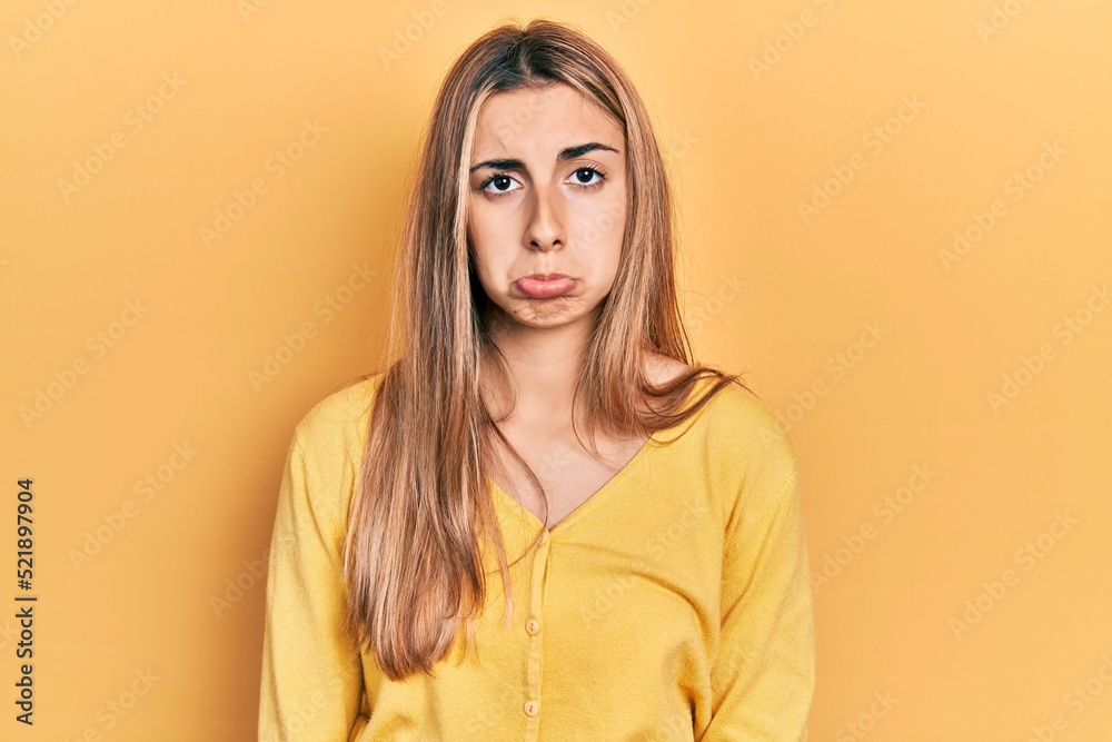 Beautiful hispanic woman wearing casual yellow sweater depressed and worry for distress, crying angry and afraid. sad expression. Beautiful hispanic woman wearing casual yellow sweater depressed and worry for distress, crying angry and afraid. sad expression.