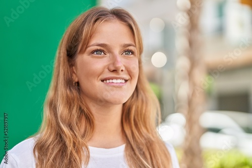 Young blonde girl smiling confident looking to the side at street