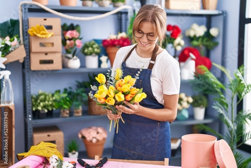 Young blonde girl florist make bouquet of flowers at florist