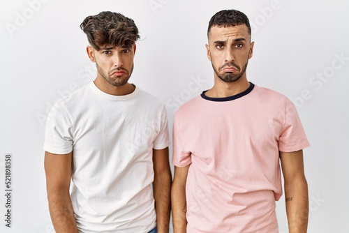 Young gay couple standing over isolated background depressed and worry for distress, crying angry and afraid. sad expression.