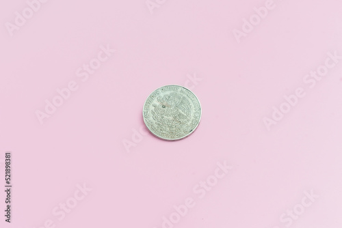 Una antigua moneda mexicana de 5 pesos, de plata de 1972, sobre fondo rosa.