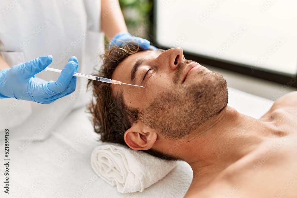 Young hispanic man having facial anti-aging treatment at beauty center Young hispanic man having facial anti-aging treatment at beauty center