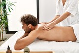 Young hispanic man having back massage at beauty center