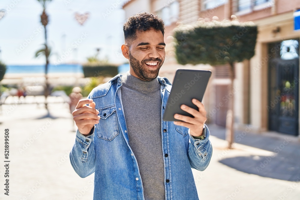 Young hispanic man smiling confident having video call at street