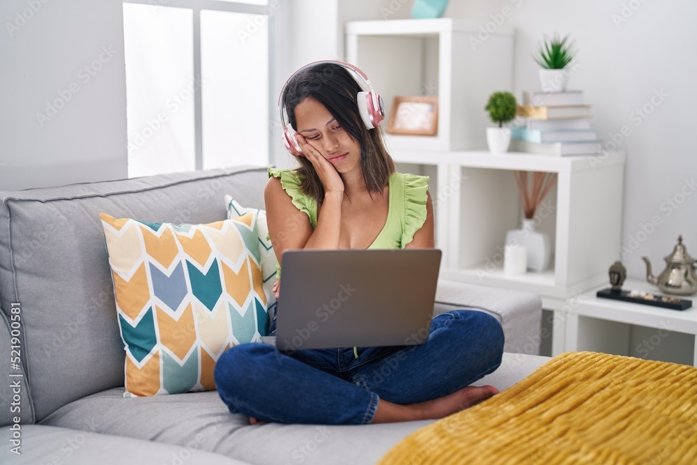 Hispanic young woman using laptop at home thinking looking tired and bored with depression problems with crossed arms. Hispanic young woman using laptop at home thinking looking tired and bored with depression problems with crossed arms.