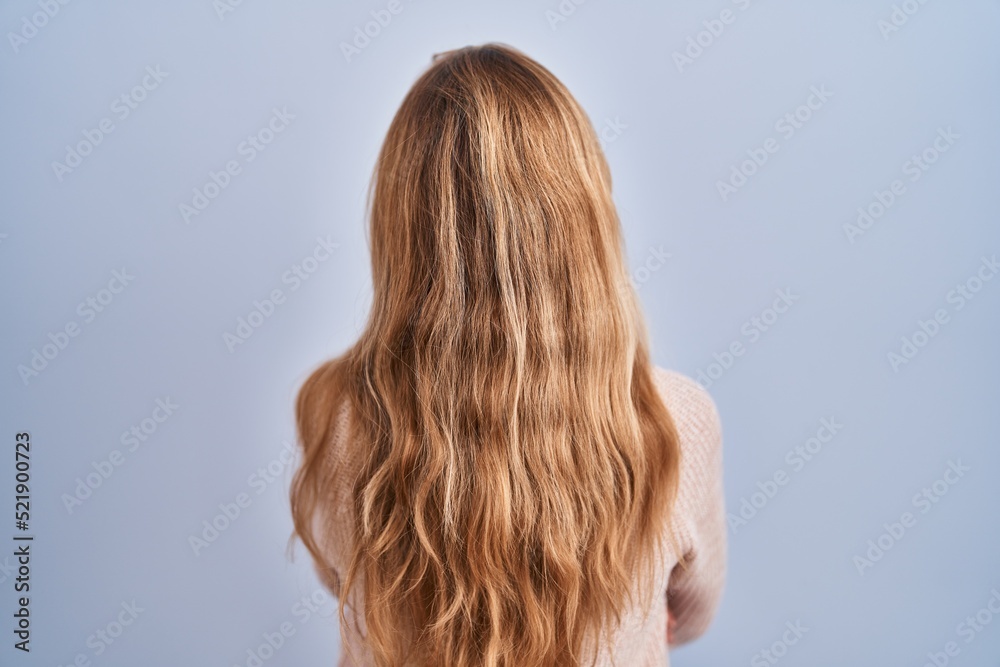 Naklejka premium Hispanic woman standing over blue background standing backwards looking away with crossed arms
