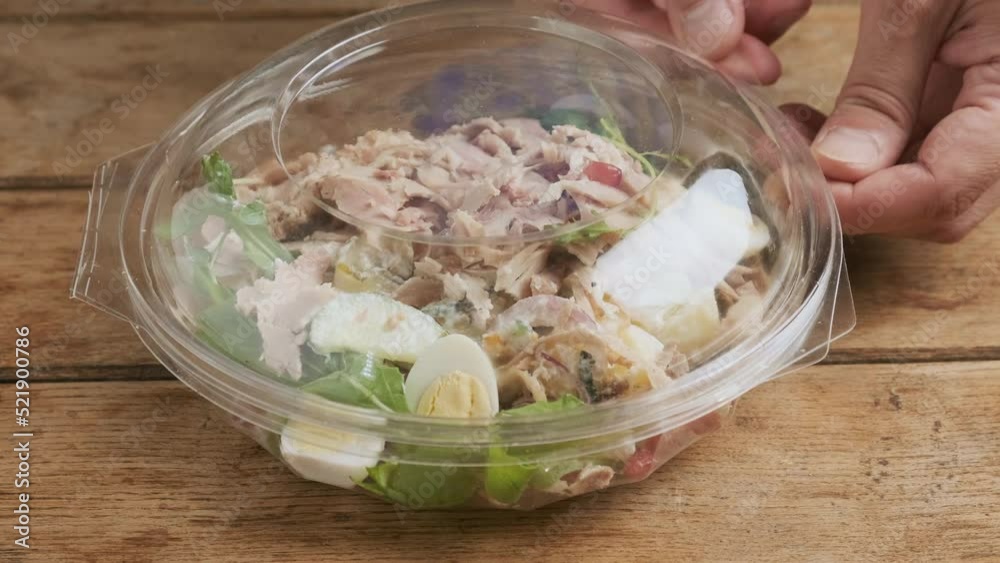 Man puts and open plastic package with healthy baked ham salad for take away or food delivery on wooden background. Food in lunch box. 4k video Man puts and open plastic package with healthy baked ham salad for take away or food delivery on wooden background. Food in lunch box. 4k video