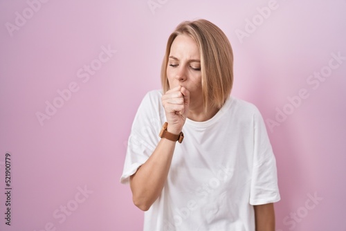 Young caucasian woman standing over pink background feeling unwell and coughing as symptom for cold or bronchitis. health care concept.
