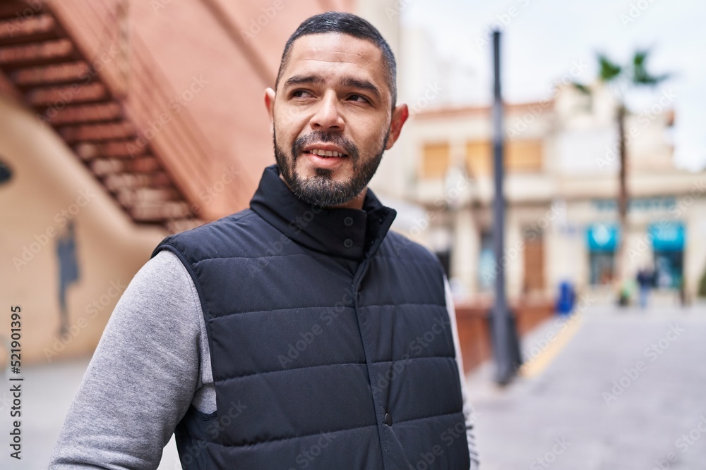 Fototapeta premium Young latin man smiling confident looking to the side at street