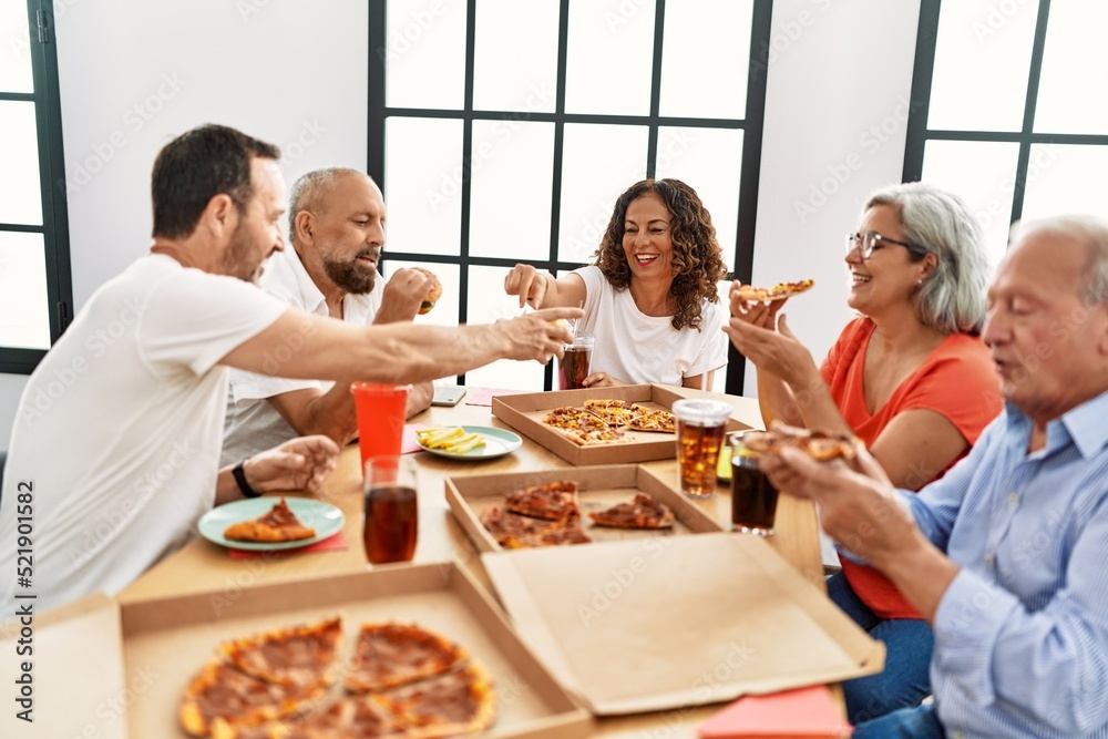 Group of middle age people smiling happy eating italian pizza sitting on the table at home Group of middle age people smiling happy eating italian pizza sitting on the table at home