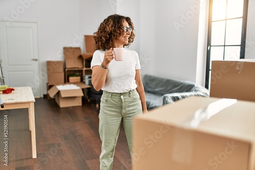 Middle age hispanic woman smiling confident drinking coffee at new home