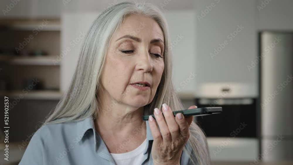 Elder lady caucasian gray-haired woman use modern technology records audio message at speakerphone send sound sms to family activate voice recognition at assistance mobile ai system no touching screen