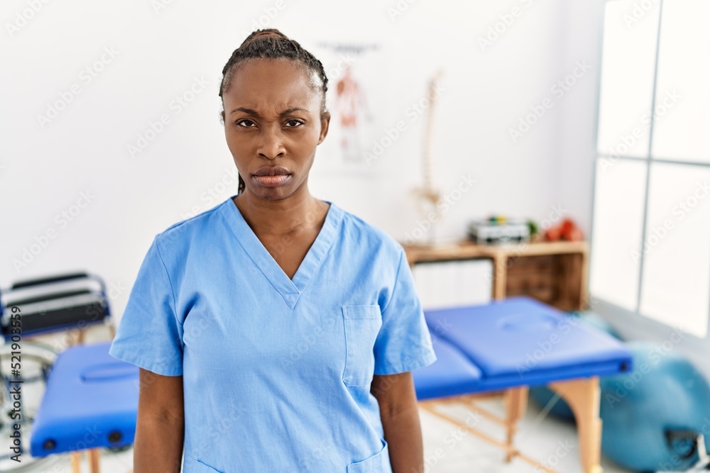 Obraz premium Black woman with braids working at pain recovery clinic skeptic and nervous, frowning upset because of problem. negative person.