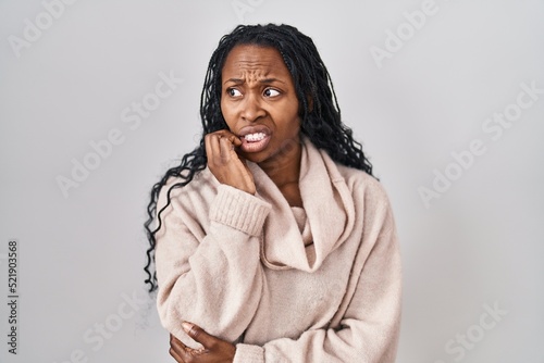 African woman standing over white background looking stressed and nervous with hands on mouth biting nails. anxiety problem.