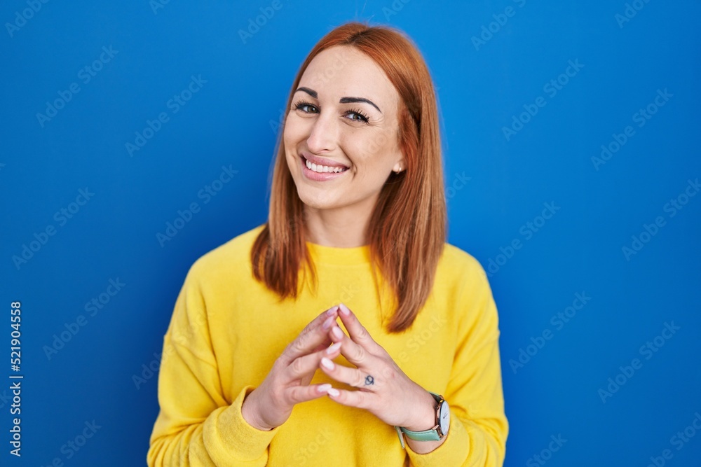 Young woman standing over blue background hands together and fingers crossed smiling relaxed and cheerful. success and optimistic Young woman standing over blue background hands together and fingers crossed smiling relaxed and cheerful. success and optimistic