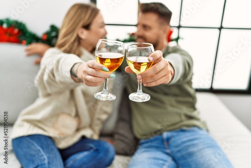 Young caucasian couple smiling happy and toasting with champange sitting on the sofa at home.