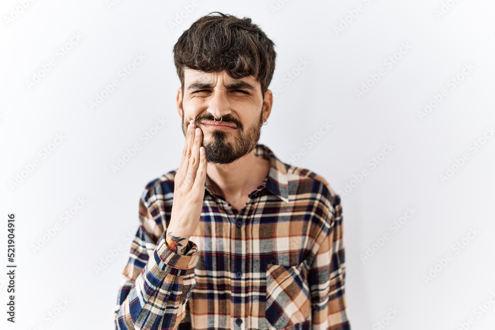 Hispanic man with beard standing over isolated background touching mouth with hand with painful expression because of toothache or dental illness on teeth. dentist Hispanic man with beard standing over isolated background touching mouth with hand with painful expression because of toothache or dental illness on teeth. dentist